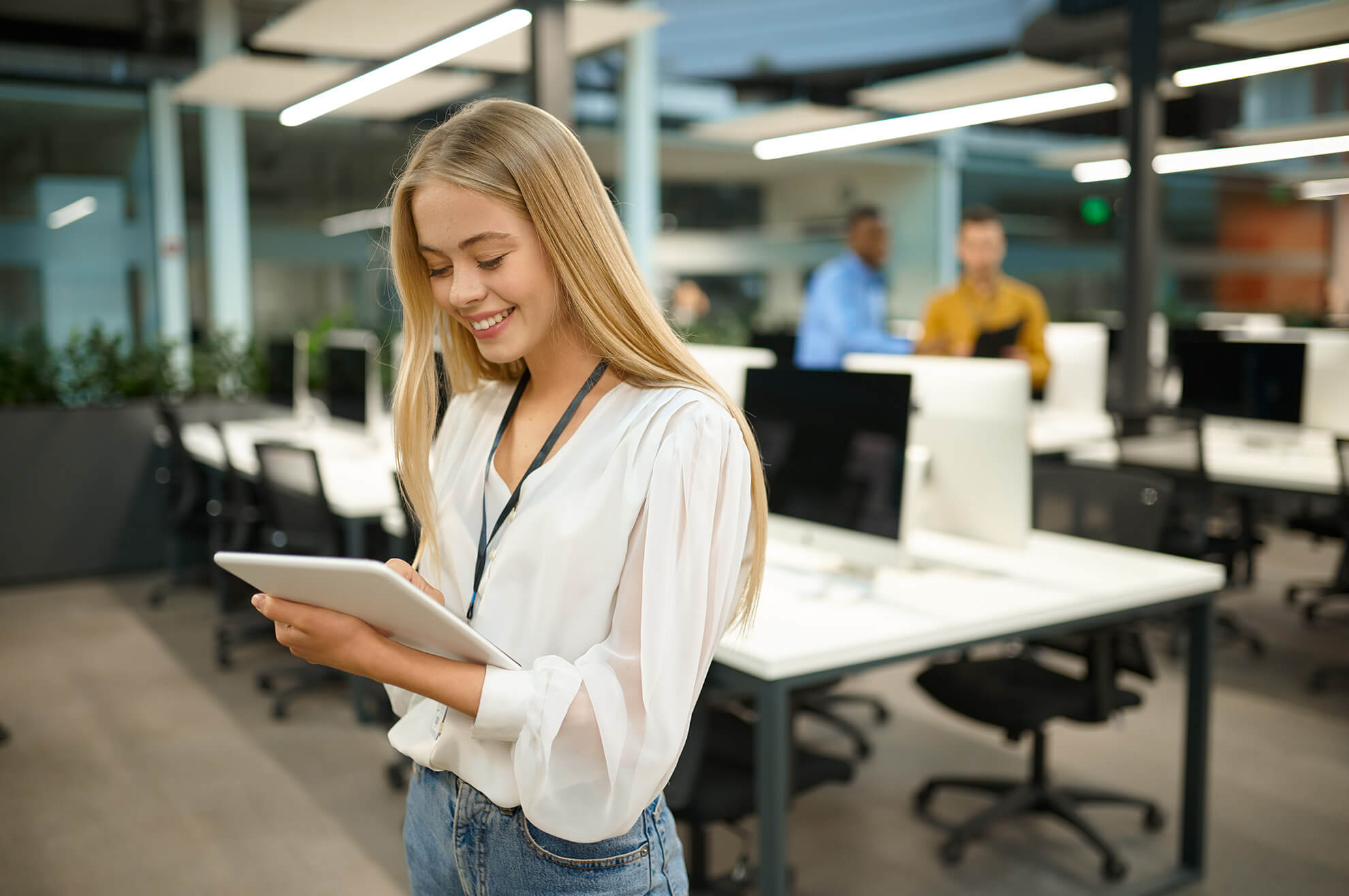 smiling female manager holds tablet device while taking scorm courses online in office
